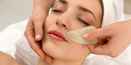  Close-up of a Gua Sha facial massage being performed on a client at DermaGlow Esthetics